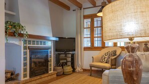 Una sala de estar acogedora con chimenea, televisor, sillón cómodo y lámpara.