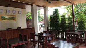 A restaurant with wooden tables and chairs, a ceiling fan, and a clock on the wall. - Le KhounSok Boutique Hotel (Luang Prabang)