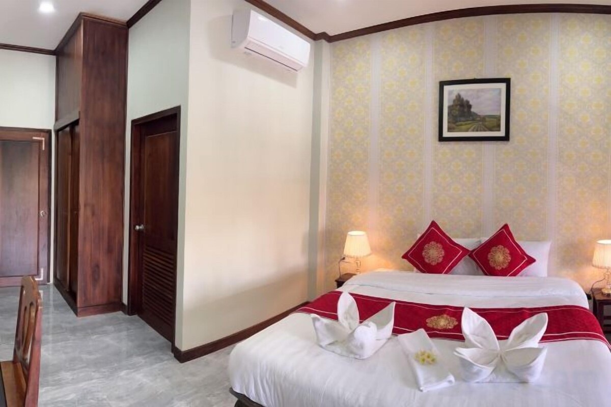 A hotel room with a bed, bedside lamps, a picture on the wall, and a door.