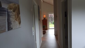 Un couloir doté d’un plancher en bois, d’un plafond avec des spots encastrés et d’une porte sur le côté droit.