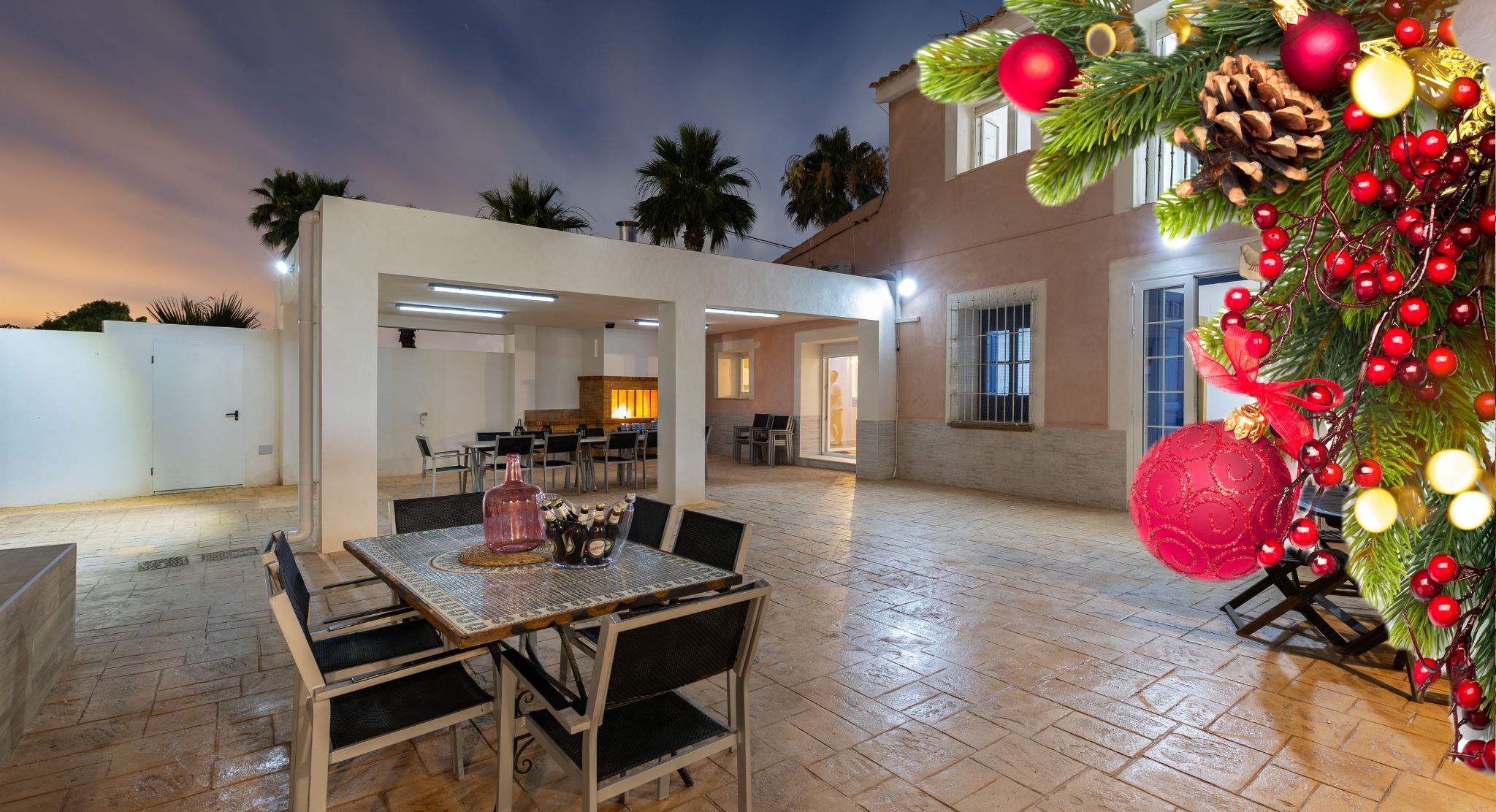 Área de estar externa com mesa, cadeiras e um pinheiro de Natal.