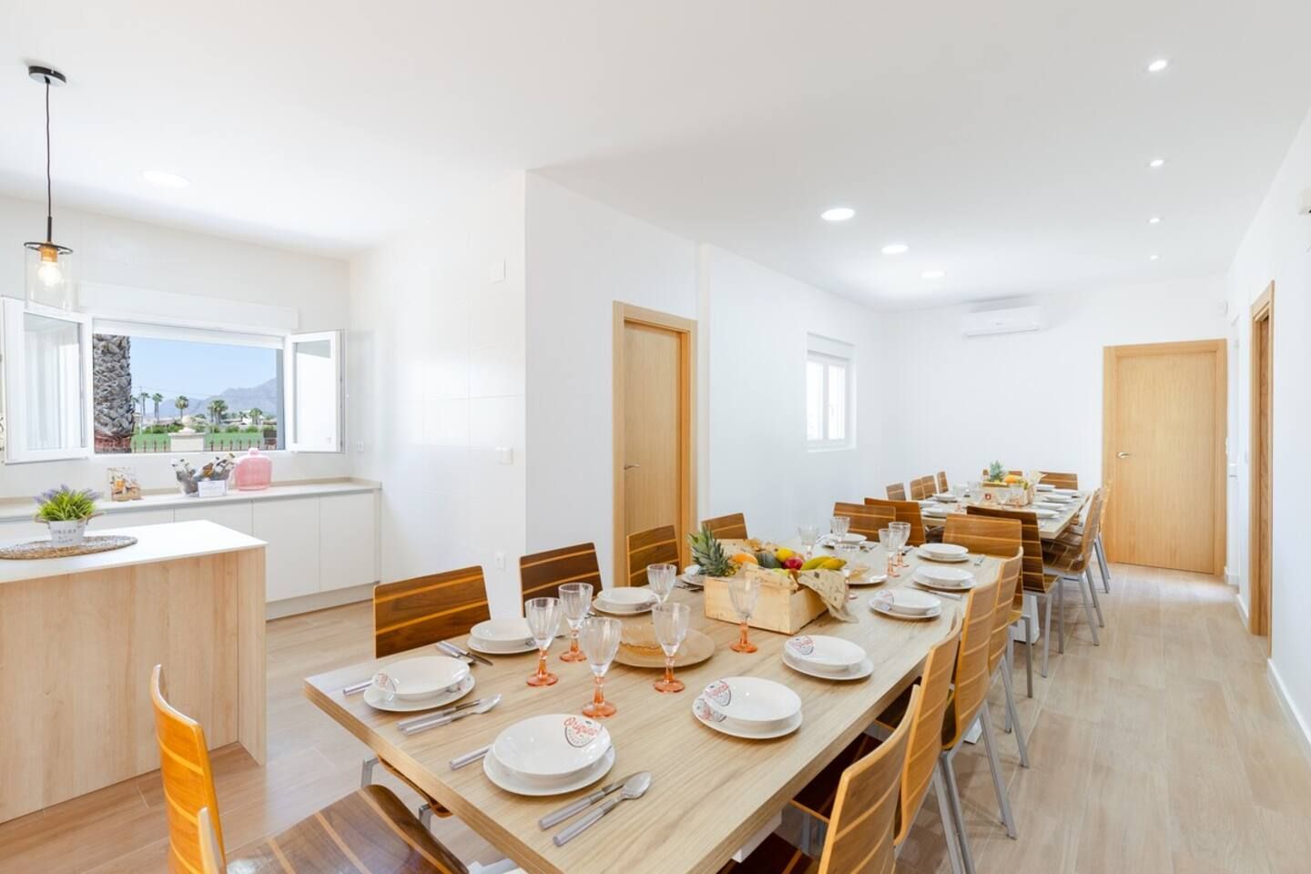 A spacious dining area with a long wooden table set for a meal, surrounded by chairs.