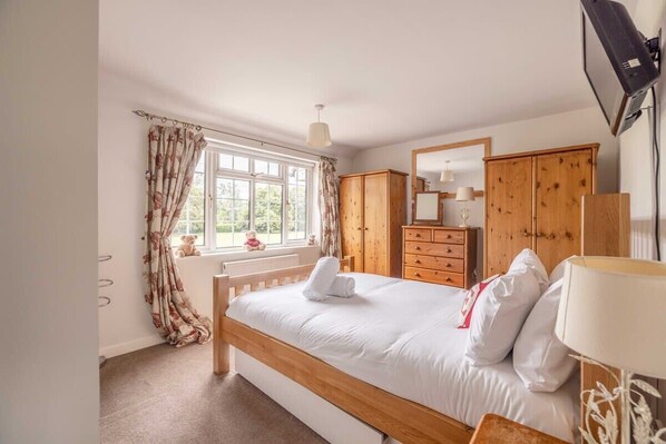 A bedroom with a bed, wooden wardrobe, and a window with curtains.