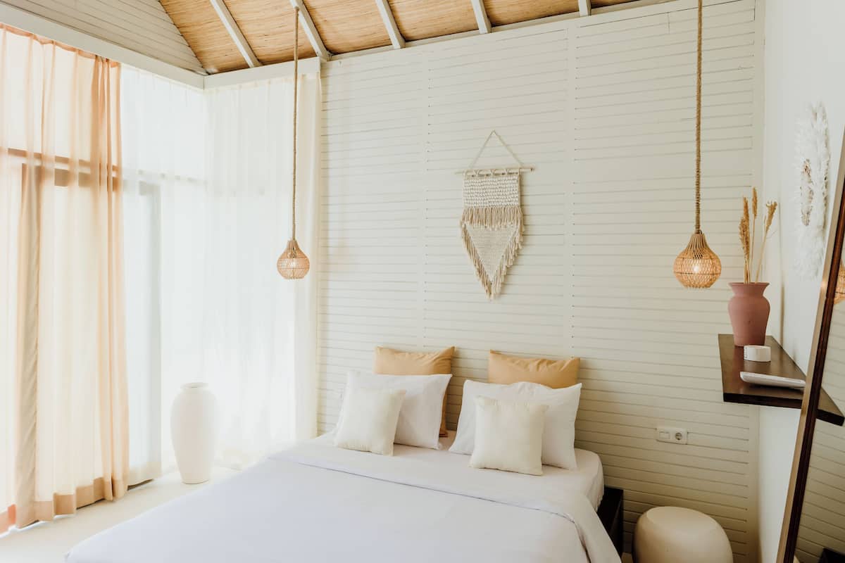 A bedroom with a bed, bedside tables, and hanging light fixtures.