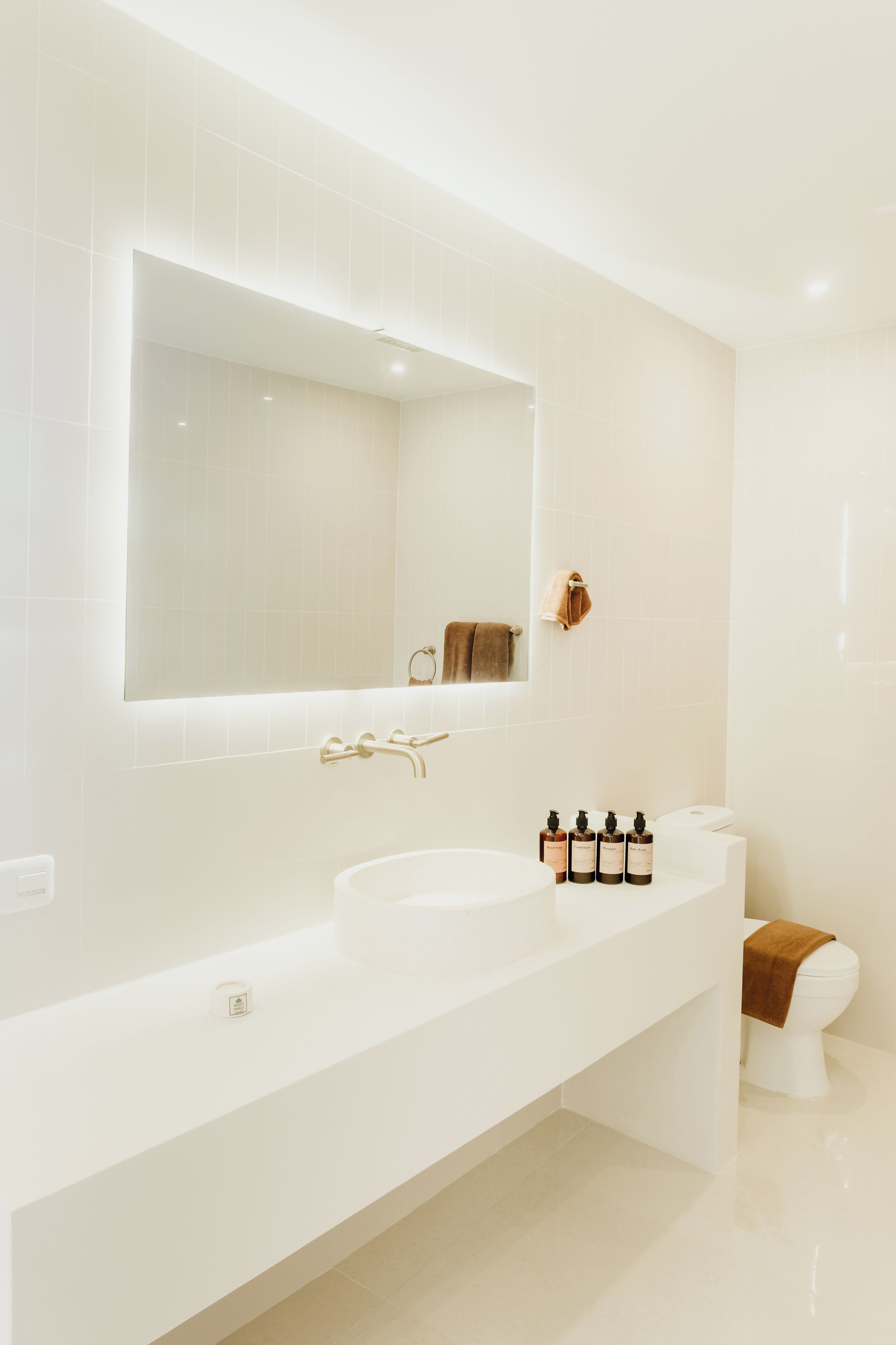 A modern bathroom with a white sink, a large mirror, and a toilet.