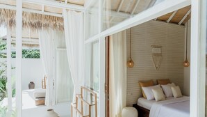 A bedroom with a bed, bedside tables, and a view of the outdoors. - The Hut Hut (Pecatu)