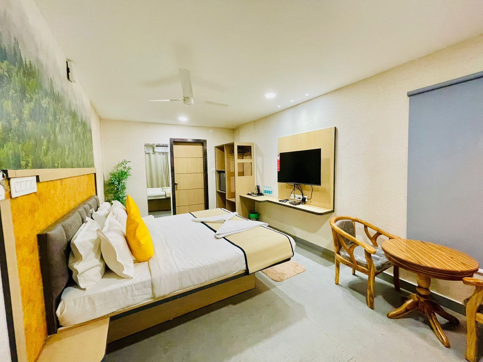 A hotel room with a bed, a desk, a chair, a television, and a ceiling fan.
