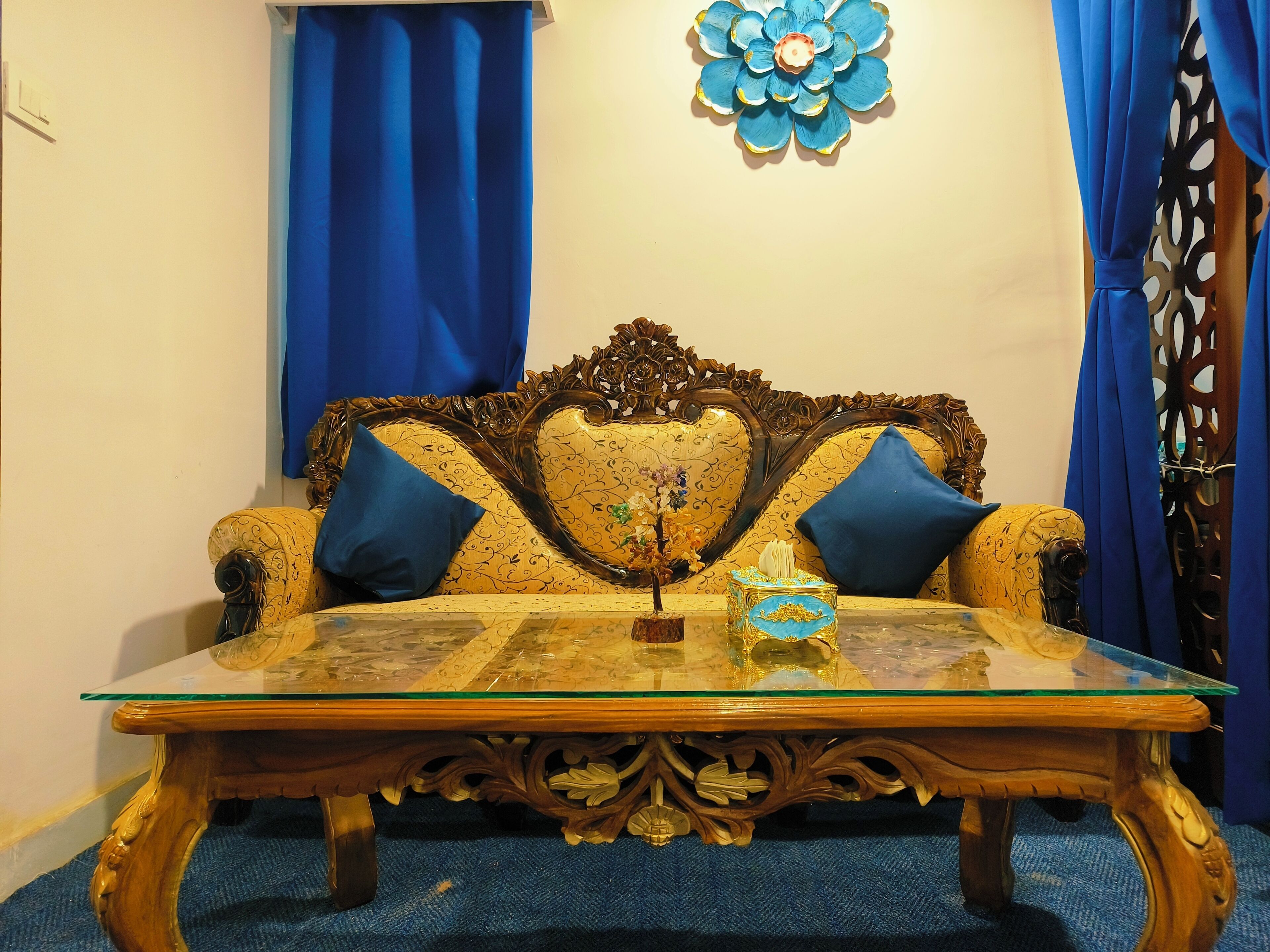 Una habitación con sofá, una mesa de centro de vidrio y cortinas azules.