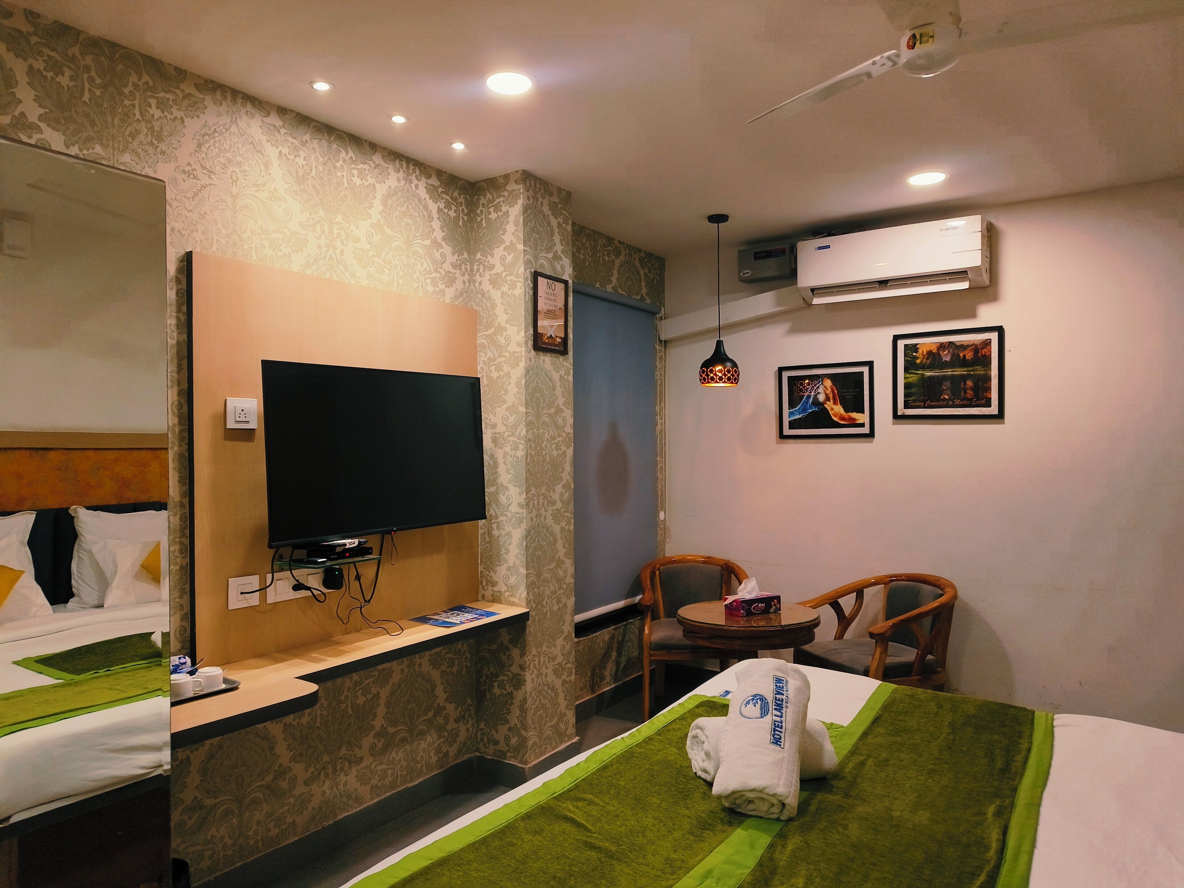 A hotel room with a bed, a television, a desk, a chair, and an air conditioning unit.