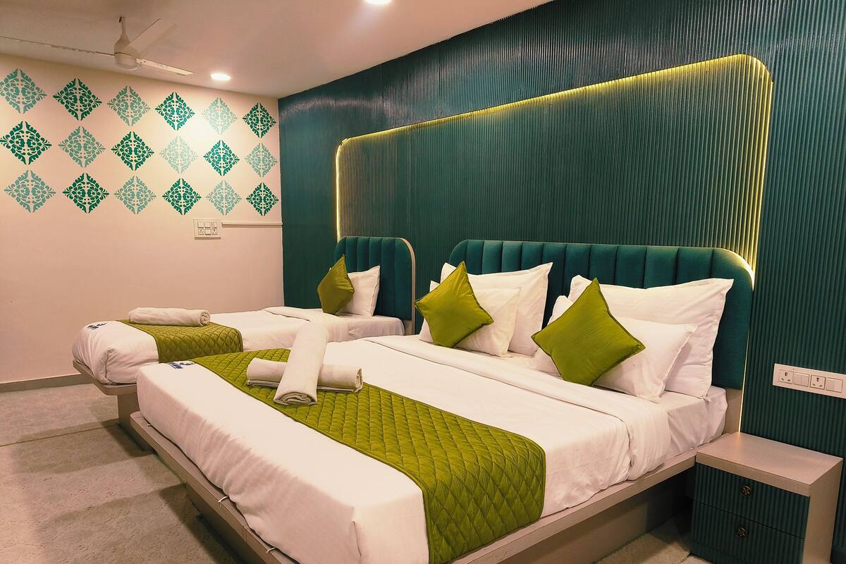 Een moderne hotelkamer met een groot bed, beddengoed in groen en wit, een hoofdeinde met geïntegreerde verlichting en een decoratief behangpatroon.