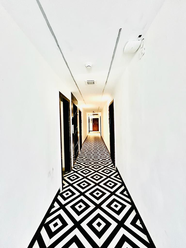 A narrow hallway with a geometric patterned floor and white walls.