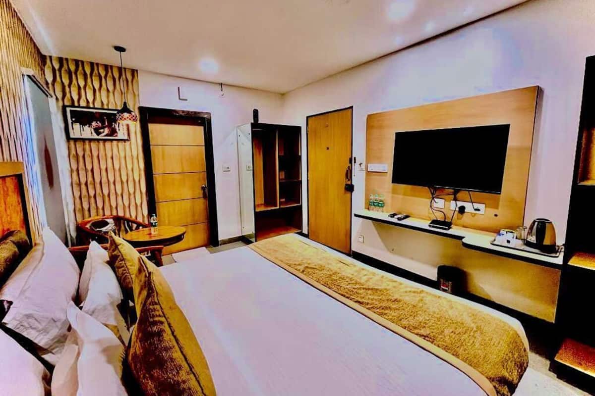 Een hotelkamer met een groot bed, een flatscreen-tv aan de wand, een bureau met een stoel en een kledingkast.