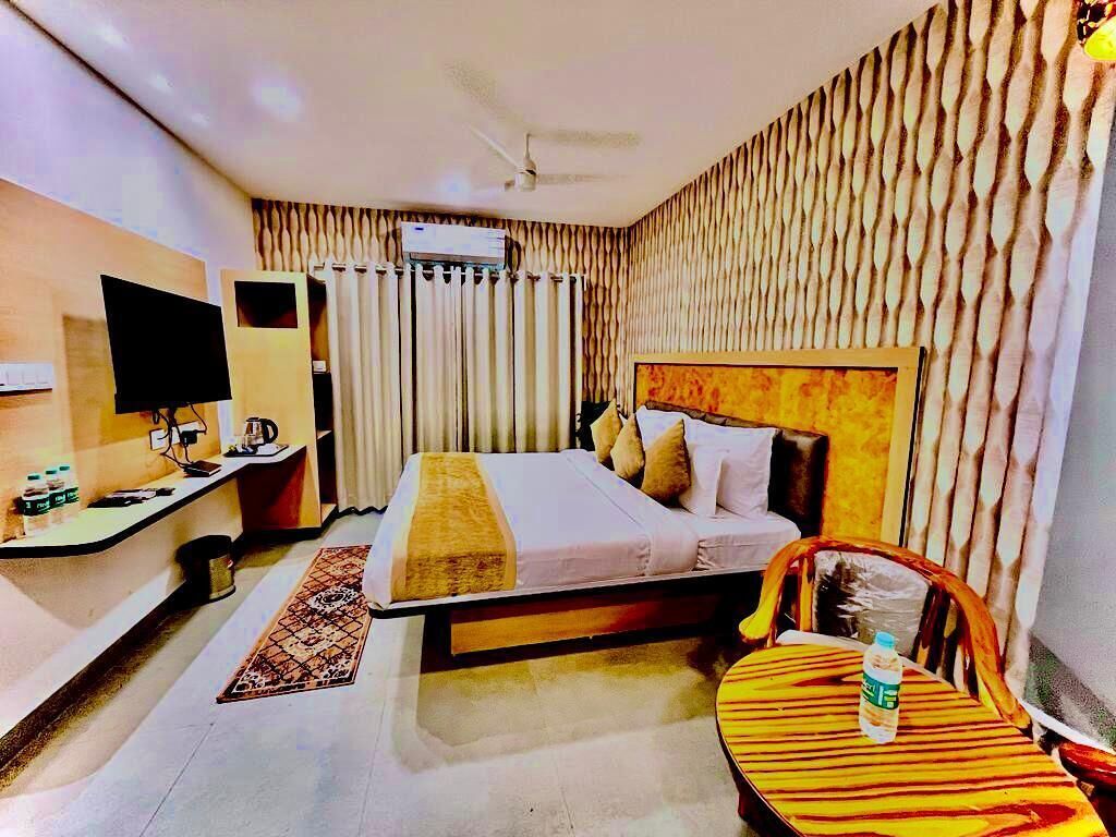 A hotel room with a bed, a desk with a computer, a chair, and a TV.