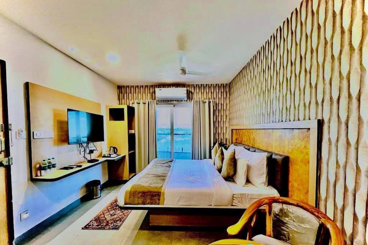 Een hotelkamer met een bed, een bureau met een flatscreen televisie, een stoel en uitzicht op het groen.
