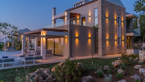 A modern multi-story house with a spacious outdoor area, including a pool and outdoor seating.
