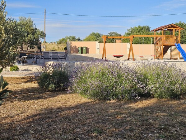 A playground with a swing set, a slide, and a small wooden structure. - Villa Zrilić ZadarVillas (Perušić Benkovački)