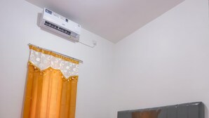 A neatly made bed with a grey headboard, two red pillows with "OYO" text, and a red blanket. An air conditioner is mounted on the wall above the bed. - OYO 92626 Good Sleep 4 Inn Dcos Syariah (Samarinda)