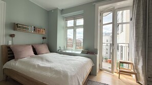 Une chambre à coucher avec un lit, une bibliothèque, une fenêtre et un balcon.