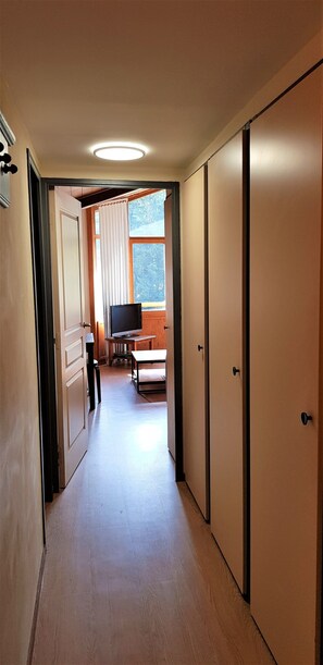 Enter a cozy space with a television and table, featuring a window with curtains and a door on either side.