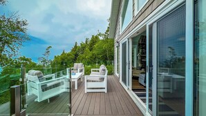 Een modern balkon met glazen hekwerk, een houten terras en buitenmeubilair.