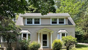 Une maison à deux étages avec un porche à l’avant, un chemin menant à l’entrée et une pelouse bien entretenue.