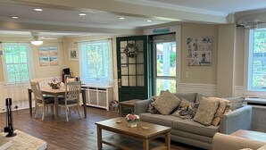 Un salon spacieux doté d’un plancher en bois, d’un canapé gris, d’une table basse et d’un coin repas avec des chaises et une table.