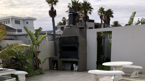 Eine Terrass mit weißen Tischen und einer Grillmöglichkeit.