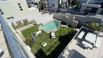 Ein Poolbereich auf dem Dach mit freiem Blick auf den Ozean, umgeben von modernen Gebäuden und ausgestattet mit Liegestühlen sowie einem kleinen Pool.