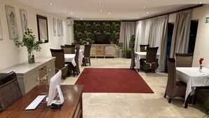 Ein Hotelzimmer mit Essbereich, Fernseher und rotem Teppich.