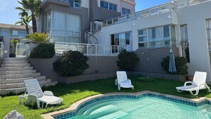 Ein modernes, zweistöckiges Haus mit Swimmingpool, Außenbereich zum Sitzen und einer Treppe, die zum oberen Stockwerk führt.