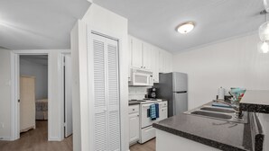 A modern kitchen with white cabinets, a microwave, a refrigerator, and a granite countertop. - New Heated Pool & Hot tub! Fantastic Ocean Views! (Galveston)