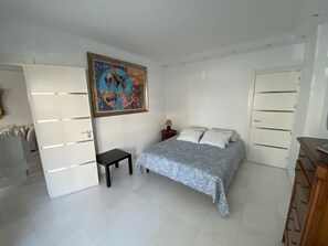 A bedroom with a bed, a nightstand, a dresser, a painting, and a wardrobe.