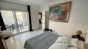 Ein Schlafzimmer mit einem Bett, einem Gemälde, einem Schreibtisch und einem Stuhl.