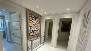 Ein Flur mit einer Glastausche und einem farbenfrohen Mosaikkunstwerk, sowie einer Tür zu einer Küche.