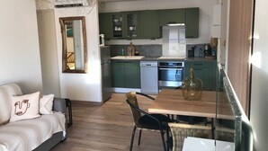 A compact living space with a kitchenette, a dining area, and a sofa with decorative pillows. - Magnifique VUE MER Golfe DE ST Tropez (La Croix-Valmer)