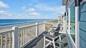 Un balcon donnant sur la plage, une chaise et une petite table.