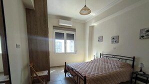 Une chambre à coucher avec un lit, une chaise, une table de chevet et une fenêtre.