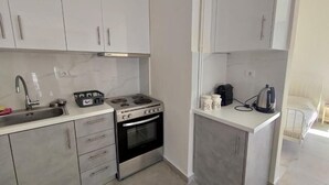 Une cuisine de taille réduite avec des meubles blancs, une cuisinière en acier inoxydable et un évier.