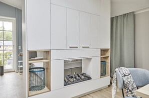 A modern living room with a built-in entertainment unit, wooden shelves, and a cozy seating area.