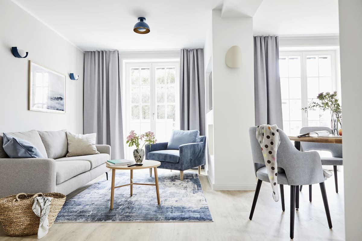 Una sala de estar moderna con un sofá, sillones, una mesa de centro y un comedor con mesa y sillas.