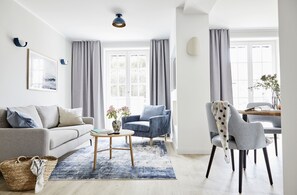 A modern living room with a sofa, armchairs, a coffee table, and a dining area with a table and chairs.