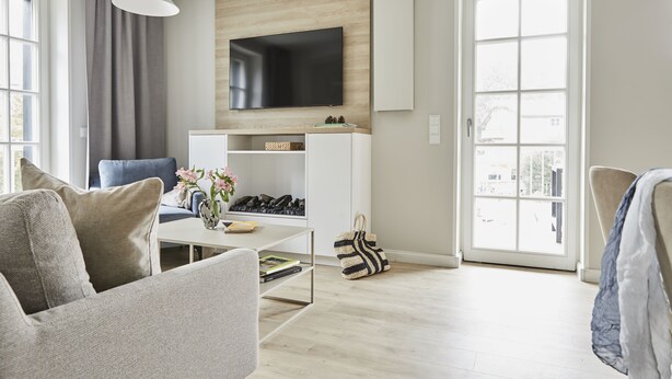 En moderne stue med et fladskærms-tv, en sofa, et sofabord og en bogreol.