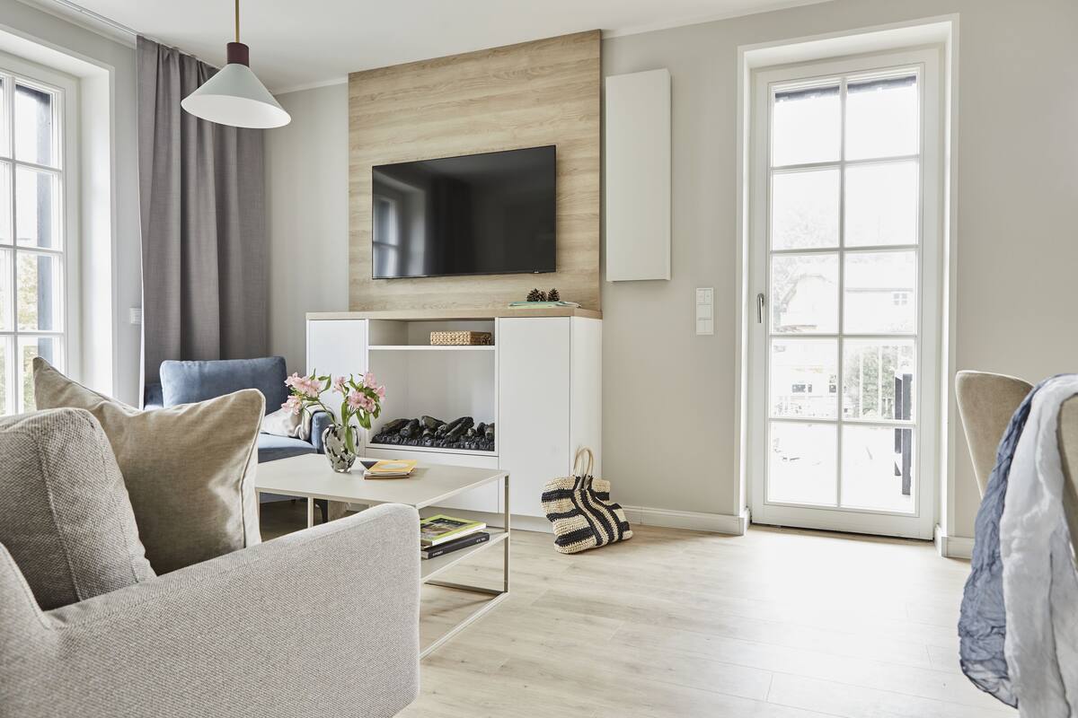 Una sala de estar moderna con un televisor de pantalla plana, un sofá, una mesa de centro y una estantería.