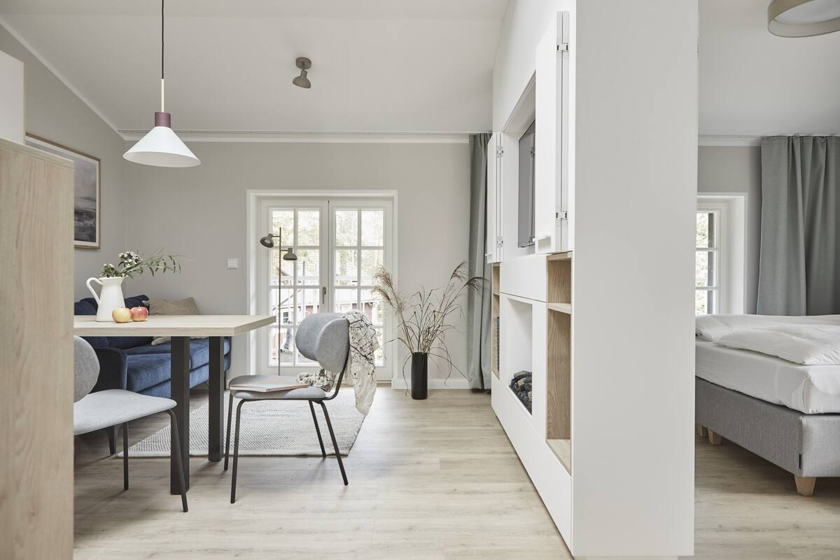 Una habitación moderna y luminosa con comedor, cama y un amplio ventanal.