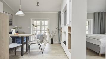 A modern, well-lit room with a dining area, a bed, and a large window.