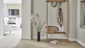 En moderne stue med et reolsystem i træ, en potteplante og et fjernsyn monteret på væggen.