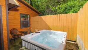 A hot tub in a wooden cabin with a wooden deck and a chair. - Studio log cabin-convenient -pet friendly-hot tub- near PF parkway! (Pigeon Forge)
