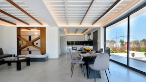 A modern interior with a dining area, kitchen, and seating space. - Villa Flamingo - Private pool, sleeps 8+, 300m away from renowned Issos Beach (Corfu)