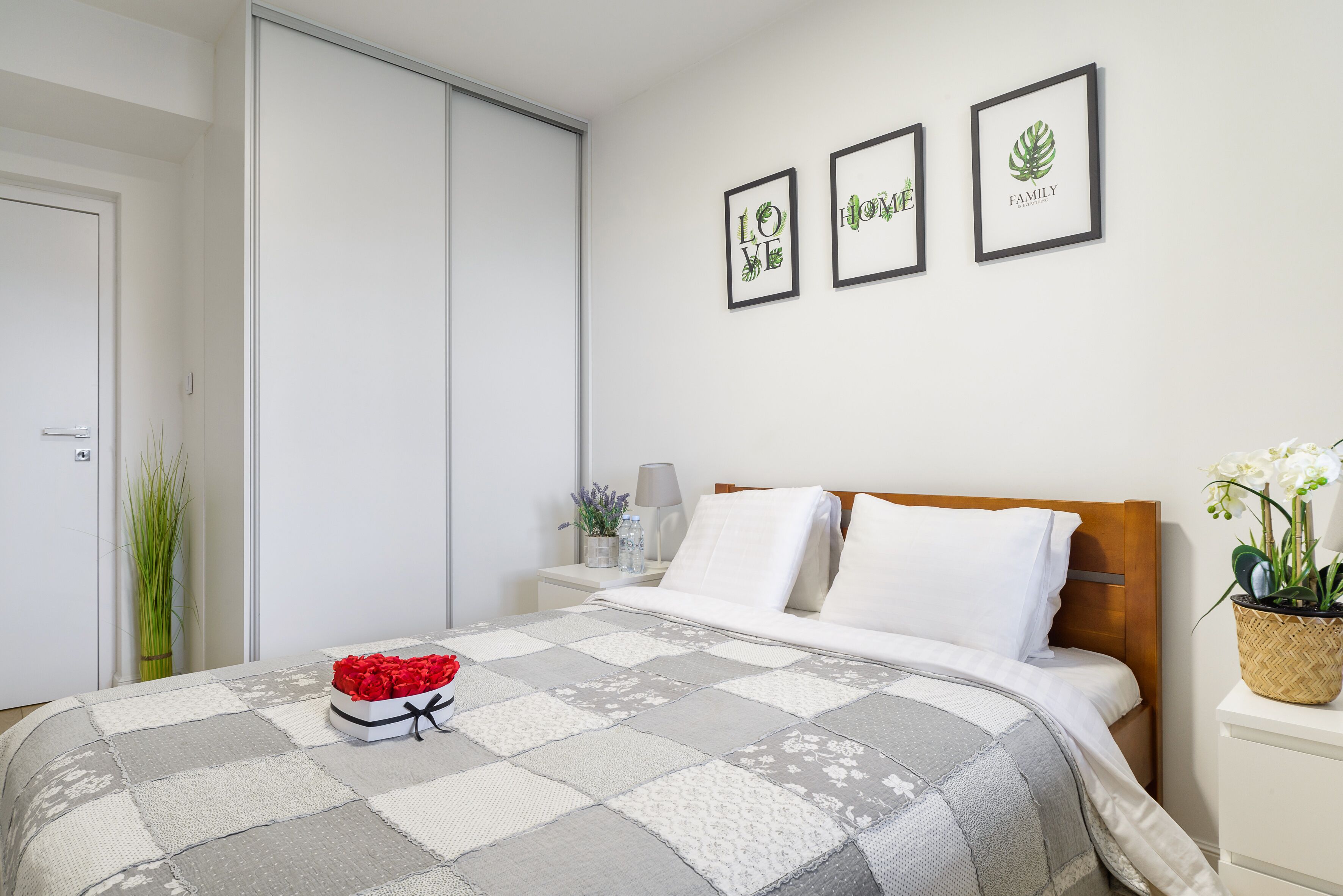 Ein Schlafzimmer mit einem Bett, einem Nachttisch, Bildern an der Wand und einer Tür.