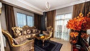 A luxurious living room with a gold and brown sofa set, a glass coffee table, and a black rug with a geometric pattern. - Blue Vista Houses & Spa (Istanbul)